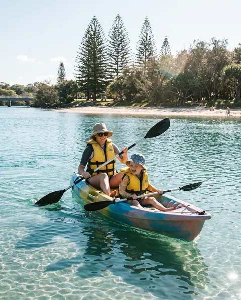Parent and child laughing in a double kayak